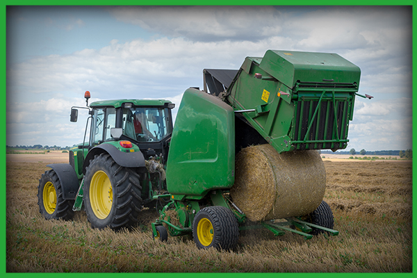 Image of a baler with a large bale of hay coming out