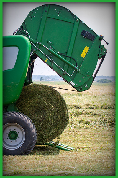 Image of a baler with a large bale of hay coming out