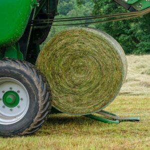Baler rolling a round bale of hay